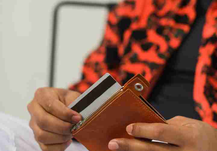 A man in a brightly patterned jacket holding a wallet and credit card